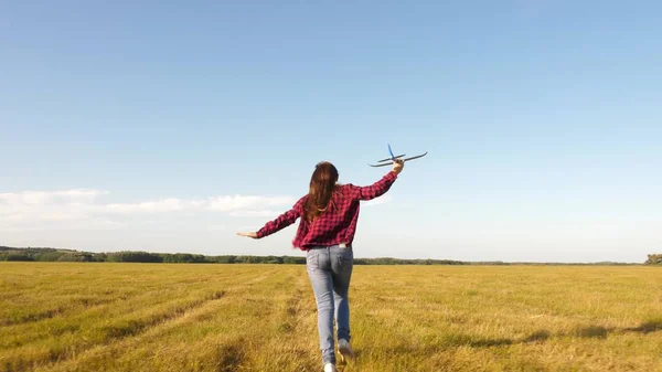 Teenager träumt davon zu fliegen und Pilot zu werden. glückliches Mädchen rennt mit einem Spielzeugflugzeug auf einem Feld im Sonnenuntergang. Kinder spielen Spielzeugflugzeug. Das Mädchen will Pilotin und Astronautin werden. Zeitlupe — Stockfoto