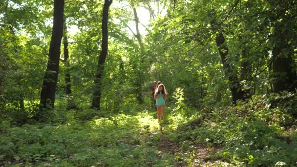 Pai e filhas, as crianças viajam no parque no verão. Família em férias viaja na floresta. amigos-turistas vão acampar na floresta. As pessoas atravessam árvores e relva. viajantes de trabalho em equipe — Vídeo de Stock