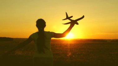 çocuklar oyuncak uçak oynarlar. Mutlu kız gün batımı ışığında bir alanda bir oyuncak uçak ile çalışır. uçan ve pilot olma genç hayalleri. kız bir pilot ve astronot olmak istiyor.