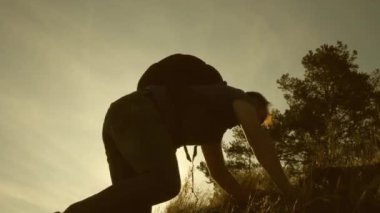 Gezgin baba, kızının dağa tırmanması için yardım elini tutar. Gün batımında seyahat eden çocuklu turist ailesi. Baba, sırt çantalı çocuklar, dağa tırmanıyorlar. turistik ekip çalışması