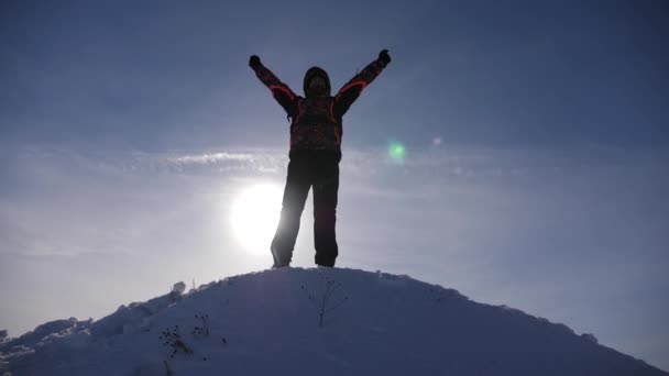 Viaggiatore si rallegra della sua vittoria in cima a una collina innevata, salta e ondeggia le braccia, un uomo felice. felice turista — Video Stock