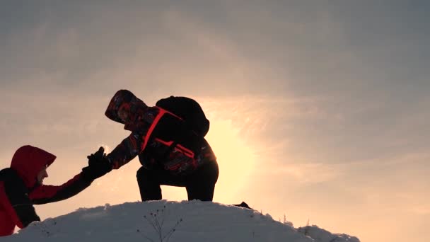 Erkekler ellerini tutup diğer her günbatımında zirveye uzanan yüksek karlı dağın zirvesine fethetmek için yardım. Ne zaman seyahat etmek soğuk doğal koşulları. Cesur için aşırı artışların — Stok video