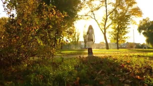 Bambino allegro corre lungo il percorso. madre e figlia stanno camminando nel parco autunnale. Mamma e bambino stanno giocando nel parco cittadino. il bambino corre su prato inglese in bei raggi del sole. famiglia felice che riposa nella natura — Video Stock