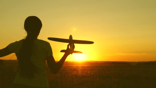 Дети играют в игрушечный самолет. Счастливая девушка бежит с игрушечным самолетом на поле при закате солнца. подросток мечтает летать и стать пилотом. девушка хочет стать летчиком и космонавтом . — стоковое видео