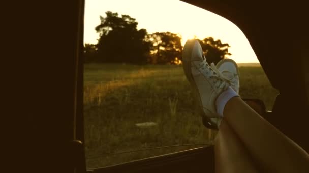 Vrouw reist met de auto. jonge vrouw houdt van reizen in een auto, het zetten van haar benen uit een open raam. Benen van een meisje in een autoruit, schittering van de zon, rijden op een auto op een landweg. — Stockvideo