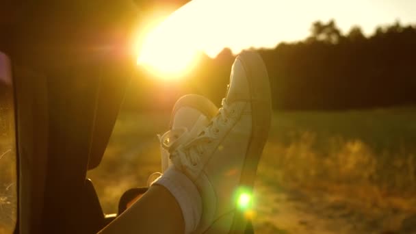 一个女孩的腿在车窗里，阳光耀眼，在乡下小路上骑着车。一个年轻女子喜欢在车里旅行，把腿从开着的窗户里伸出来. — 图库视频影像