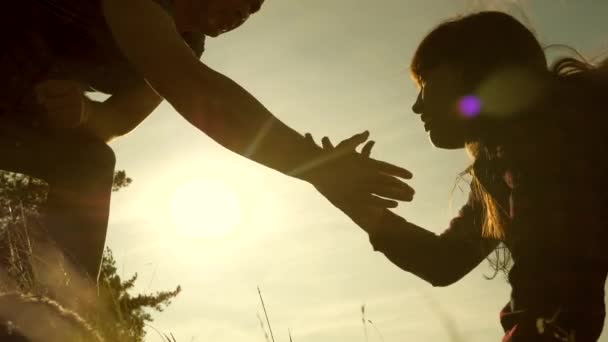 Vader houdt zijn hand te helpen kinderen klimmen berg. Familie van toeristen met kinderen die bij zonsondergang reizen. Papa, kinderen en moeder met rugzakken reizen klim berg in de zon. toeristisch teamwork — Stockvideo