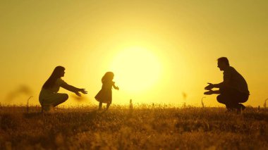 Ebeveynler küçük kızları ile oynarlar. anne ve baba güneşte kızları ile oynamak. mutlu bebek babadan anneye geçer. genç aile alanında bir çocuk 1 yıl. aile mutluluğu kavramı.