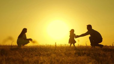 Ebeveynler küçük kızları ile oynarlar. anne ve baba güneşte kızları ile oynamak. mutlu bebek babadan anneye geçer. genç aile alanında bir çocuk 1 yıl. aile mutluluğu kavramı.