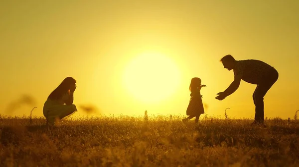 Parents play with their little daughter. mother and Dad play with their daughter in sun. happy baby goes from dad to mom. young family in the field with a child 1 year. family happiness concept. — Stock Photo, Image