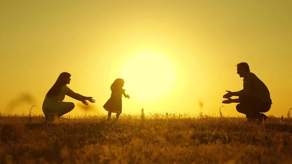 Родители играют со своей маленькой дочерью. Мама и папа играют со своей дочерью на солнце. счастливый ребенок переходит от папы к маме. молодая семья в поле с ребенком 1 год. семейное счастье . — стоковое фото