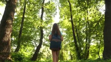 bir sırt çantası ile mutlu kız gezgin ormanda farklı yönlere kollarını yayan döner ve meditasyon. Yürüyüşçü kadın ormanda yürüyor. yaz parkında mutlu yürüyüşçü kız. genç maceralar .