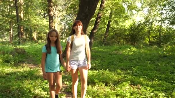 Уставшие девушки-путешественницы с рюкзаками проходят через заросли в лесу. Женщина-туристка гуляет по лесу. Счастливая девушка-туристка в летнем парке. подростковые приключения в отпуске . — стоковое видео