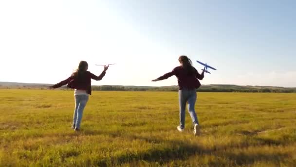 Παιχνίδι αεροπλάνο στα χέρια των κοριτσιών που παίζουν στο χωράφι. Ευτυχισμένα παιδιά σε ένα λιβάδι με ένα αεροπλάνο στο χέρι. Όνειρα για πτήσεις. έννοια της ευτυχης παιδικής ηλικίας. Σιλουέτα των παιδιών που παίζουν σε ένα αεροπλάνο. — Αρχείο Βίντεο