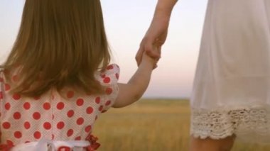 bebek annelerin elini tutar, mutlu bir aile şehir dışında akşam yürür. Annem küçük kızıyla birlikte sahada yürüyor. Anne ve bebek parkta dinleniyor. çocuk çayırda annesi ile oynar.
