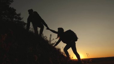 turistler gün batımında el ele tutuşarak goy aşağı inerler. erkek gezgin, tepenin tepesinden inen bir kadın yolcunun elini tutar. iş adamlarının takım çalışması. Mutlu aile tatilde.