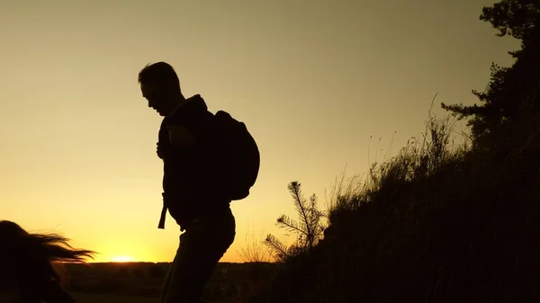 Male traveler and female traveler descend from the top of the hill. teamwork of business people. tourists descend from the mountain in the sunset, one after another. Happy family on vacation. — Stock Photo, Image