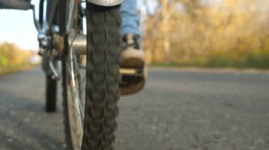 çocuk parkta bir bisiklet ile seyahat. genç kız yürüyor. Genç bir kız yolda yürür ve bisiklete biner. Genç bisiklet ile sonbahar yürümek. sportif yaşam tarzı. Yavaş çekim