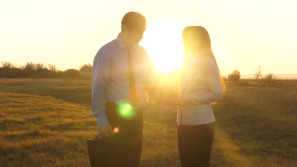 Hombre de negocios con un maletín y una mujer de negocios reunión de negocios en un parque. trabajo en equipo de los socios comerciales en la luz del atardecer. Movimiento lento . — Vídeos de Stock