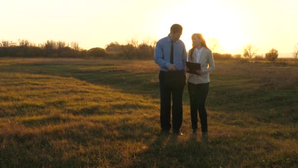 Le travail d'équipe des partenaires commerciaux à la lumière du coucher du soleil. Au ralenti. homme d'affaires avec une mallette et femme d'affaires réunion d'affaires dans un parc . — Video