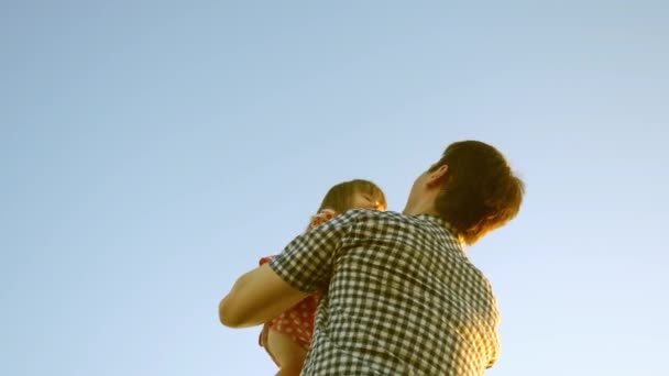 Pai e criança brincam, riem e abraçam juntos. O pai vomita uma filha feliz no céu azul. appy família viaja. Bebê nos braços dos pais. Dia de folga do pai. O conceito de uma família feliz — Vídeo de Stock