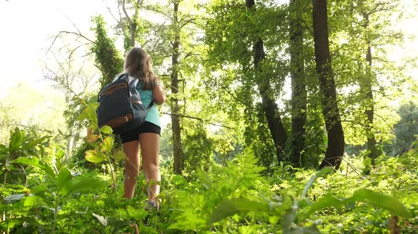 Vandrare Girl Tourist gör sin väg genom sncket. tonåring äventyr. lycklig tjej resenär med en ryggsäck snurrar i skogen sprider armarna i olika riktningar och mediterar. — Stockfoto