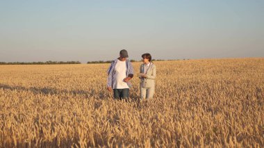Çiftçi bir iş kadınına buğday satar. Tabletli bir iş kadını ve buğday tarlasında ekip çalışması. İş kadını ve tarımcı tarladaki tahılın kalitesini kontrol ediyor. Tahıl topluyorum..