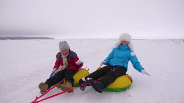 Aile Noel tatilinde kış parkında oynuyor. Mutlu anne çocuklar kışın karda kayar ve kartopu oynarlar. Anne ve kızı gülüyor ve seviniyor. Yavaş çekim — Stok video