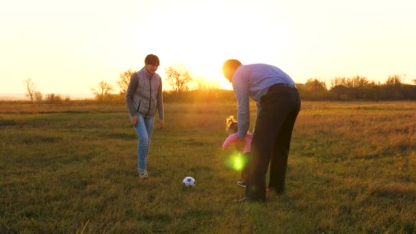 Vater spielt mit Kindern und kleiner Tochter Ball. Familie spielt mit einem kleinen Kind im Park bei Sonnenuntergang. Papa spielt mit seiner Familie Fußball. Glückliches Familienkonzept. — Stockvideo