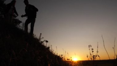 turistler gün batımında el ele tutuşarak goy aşağı inerler. erkek gezgin, tepenin tepesinden inen bir kadın yolcunun elini tutar. iş adamlarının takım çalışması. Mutlu aile tatilde.