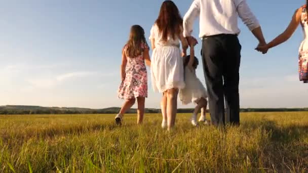 Madre, padre e hija pequeña con hermanas caminando en el campo bajo el sol. Feliz familia joven. Los niños, papá y mamá juegan en el prado bajo el sol. concepto de una familia feliz . — Vídeos de Stock