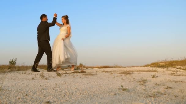 Hochzeitstanz auf Hochzeitsreise. Mann und Frau tanzen im Sand gegen den Himmel — Stockvideo