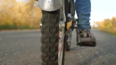 Bisiklet pedallar itmek kız bacaklar. tekerlek izleri rides, yakın çekim. asfalt yolda bisiklet sürmek.