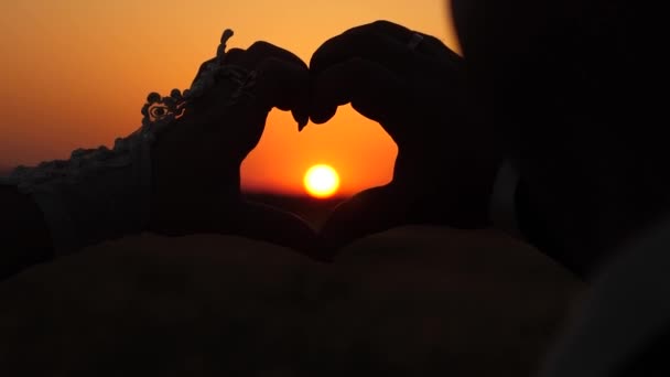 El sol está en las manos. mujer y hombre haciendo signos del corazón con las manos delante de una hermosa puesta de sol en el horizonte. Trabajo en equipo de una pareja amorosa. celebrando el éxito y la victoria . — Vídeos de Stock