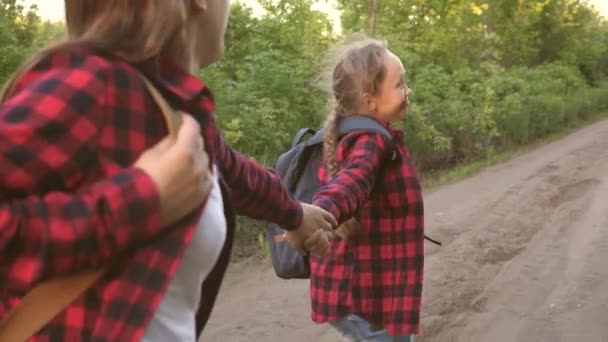 Girls travelers with backpacks run along country road holding hands in rays of the bright sun. Hiker Girl. children travelers. teen girls travel and hold hands. lets follow me — Stock Video
