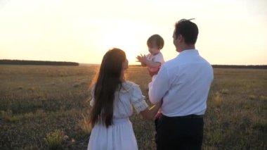 Kız parkta dinlenmek ile baba. mutlu aile ve çocukluk konsepti. Aile gün batımında bebekle oynuyor. Baba ve annem gün batımında kollarında kızı ile yürümek.