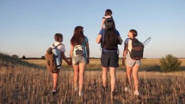 sırt çantaları ile çocuk ve baba ve anne vadi boyunca seyahat. Baba anne ve kızları kampa gidiyor. Seyahat eden turist ailesi. turistlerin takım çalışması. zafere hareket.