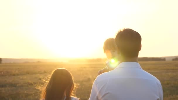 Dad and Mom walk with her daughter in her arms at sunset. family walks with a child at sunset. father with daughters resting in the park. concept of happy family and childhood. — Stock Video