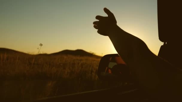 女孩们手在太阳上挥手。开车旅行。司机手是玩太阳从车窗对美丽的日落. — 图库视频影像