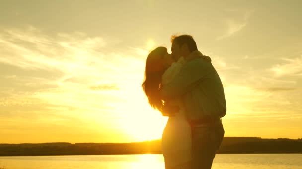 Счастливый парень и девушка вальсируют вечером в летнем парке. Любящий мужчина и женщина танцуют в ярких лучах солнца на фоне озера. Молодая пара танцует на закате на пляже . — стоковое видео