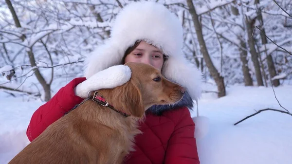 dog kisses the hostess. dog licks girls face. Beautiful girl smiles, caresses her beloved dog in winter in park. girl with hunting dog walks in winter in forest.