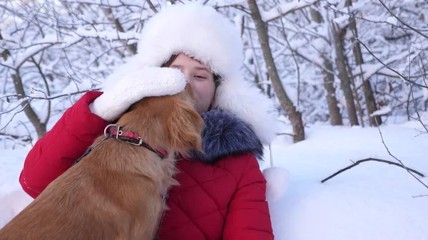Hund küsst Gastgeberin. Hund leckt Mädchen Gesicht. schöne Mädchen lächelt, streichelt ihren geliebten Hund im Winter im Park. Mädchen mit Jagdhund geht im Winter im Wald spazieren. — Stockfoto