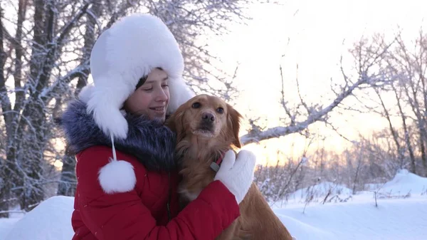Ein Kind spielt an Weihnachten mit seinem Haustier im Wald. schöne Mädchen lächelt, streichelt ihren geliebten Hund im Winter im Park. Mädchen mit einem Jagdhund geht im Winter im Wald spazieren. Hund küsst Wirtin. — Stockfoto