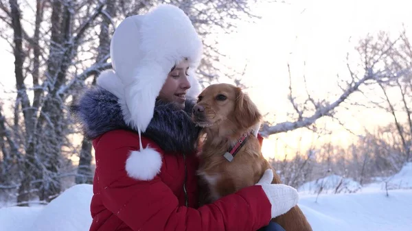 Ein Kind spielt an Weihnachten mit seinem Haustier im Wald. schöne Mädchen lächelt, streichelt ihren geliebten Hund im Winter im Park. Mädchen mit einem Jagdhund geht im Winter im Wald spazieren. Hund küsst Wirtin. — Stockfoto