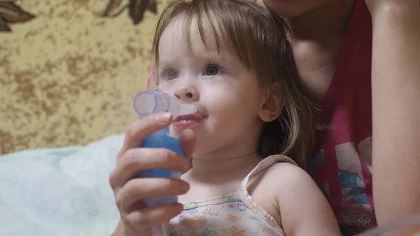 Child is sick and breathes through an inhaler. Toddler treats flu by inhaling inhalation vapor. little girl treated with an inhalation mask on her face in a hospital. — Stock Photo, Image