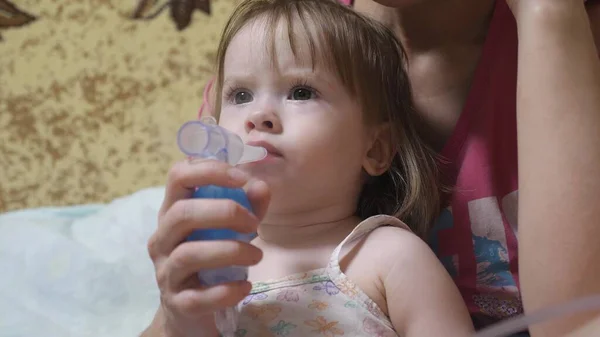 Child is sick and breathes through an inhaler. Toddler treats flu by inhaling inhalation vapor. little girl treated with an inhalation mask on her face in a hospital. — Stock Photo, Image