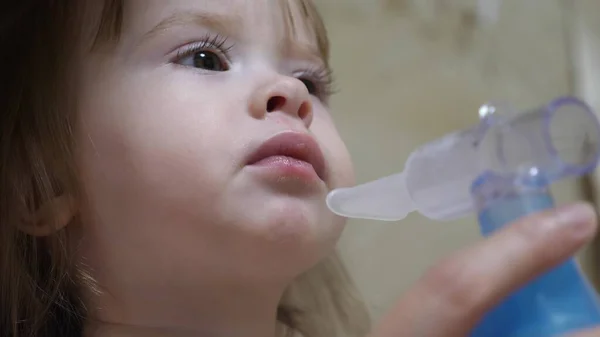 Little girl treated with an inhalation mask on her face in a hospital. child is sick and breathes through an inhaler. Toddler treats flu by inhaling inhalation vapor. — Stock Photo, Image