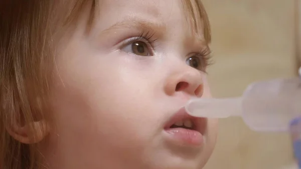 Dziecko jest chore i oddycha przez inhalator. zbliżenie. Dziewczynka leczona maską inhalacyjną na twarzy w szpitalu. Maluch leczy grypę poprzez wdychanie oparów wziewnych. — Zdjęcie stockowe