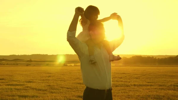 Концепция счастливого детства. Папа с маленькой дочерью на плечах ходят и смотрят на прекрасный закат. Семья, отец играет со своим маленьким ребенком в парке. концепция командной работы и роста в — стоковое фото