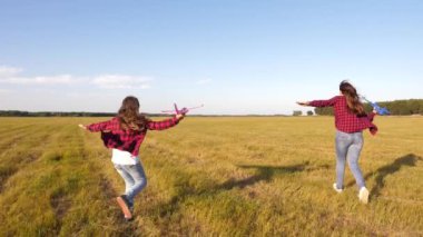 çocuklar oyuncak uçak oynarlar. gençler pilot ve astronot olmak istiyorum. Mutlu kızlar gün batımında sahada oyuncak uçakla koşarlar. mutlu bir çocukluk kavramı. Kızlar uçmayı ve pilot olmayı hayal.